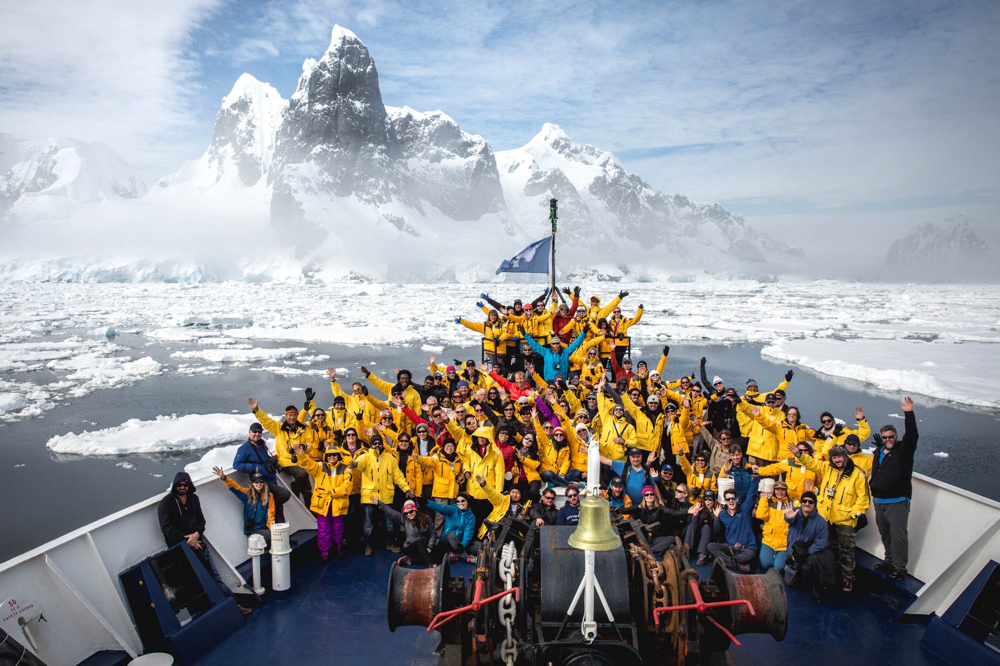 Passengers pose for a group photo on the bow of the ship