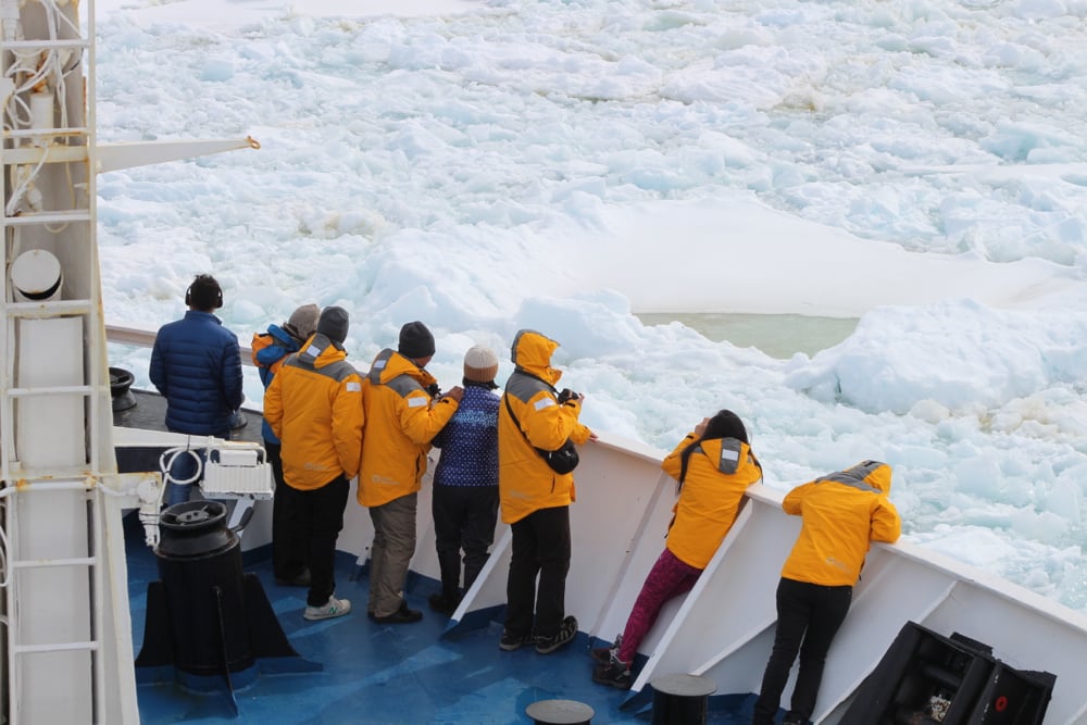 Passengers watch on deck as Ocean Diamond powers its way through Antarctic sea ice
