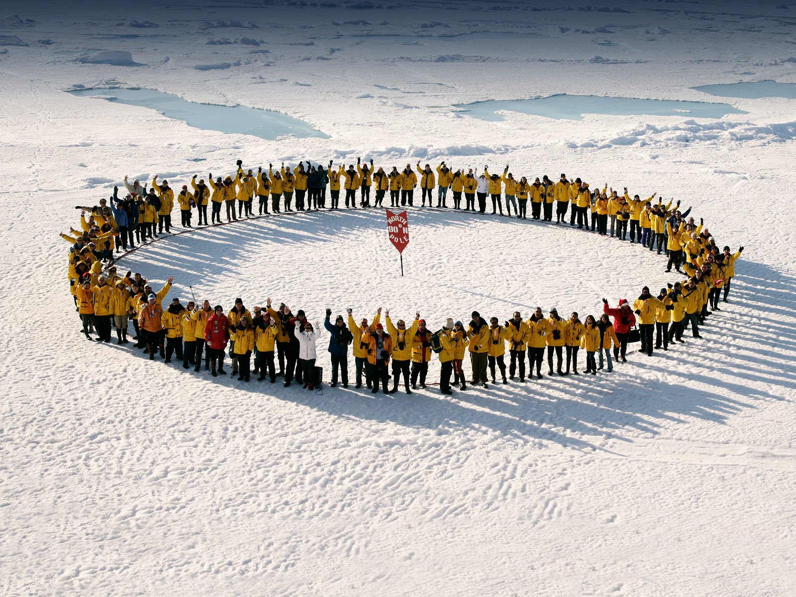 Passengers gather on the sea ice to celebrate the feat of reaching the North Pole by small expedition ship. Photo: John Weller